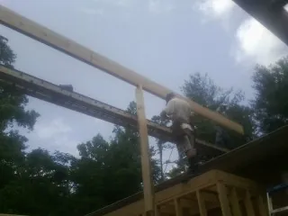 Carpenter setting a ridge beam over a new addition frame — Ice Dam Removal by Roofing Brothers in Randolph