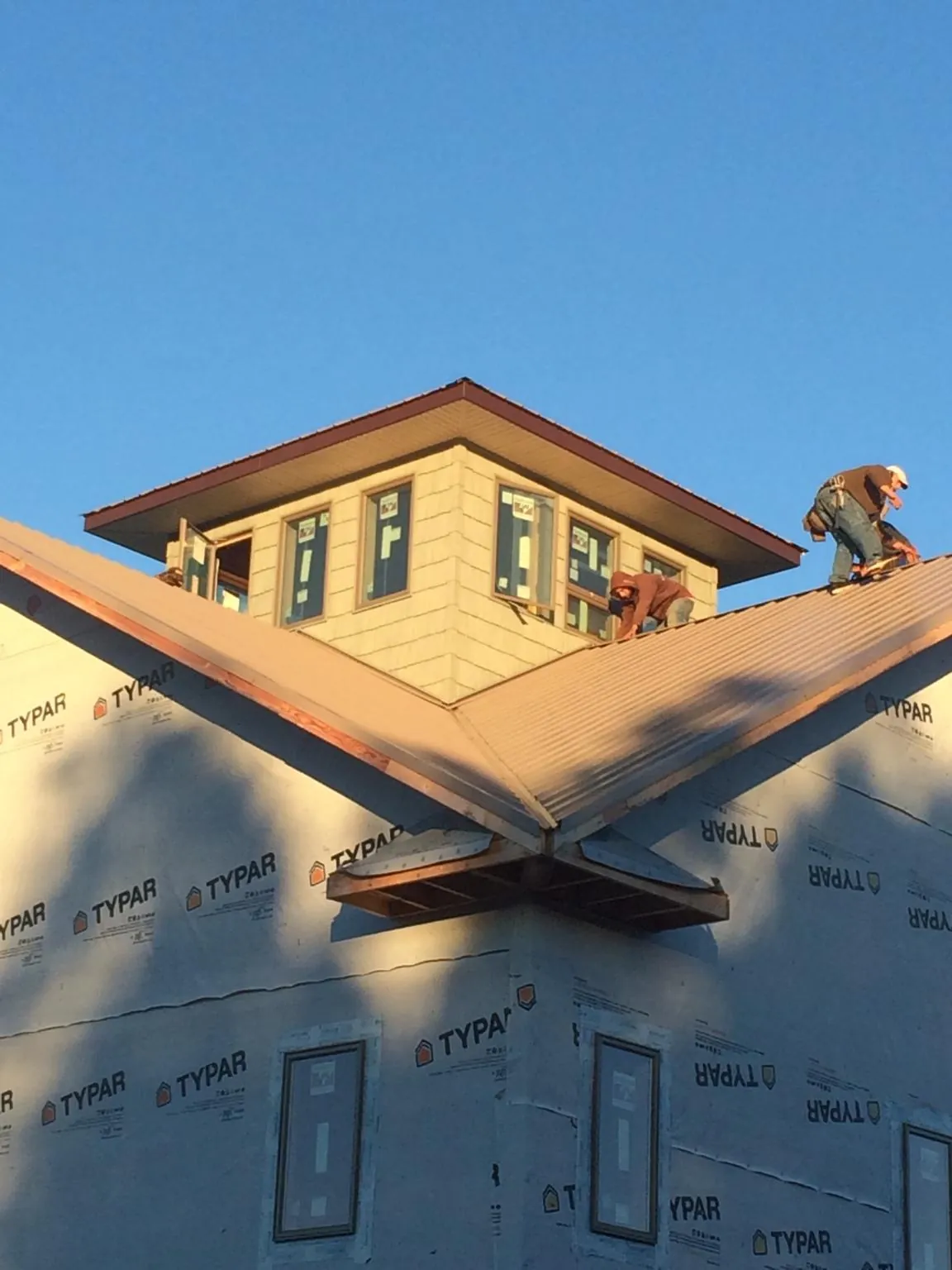 Roofers working around a rooftop cupola on a new metal roof at sunset — Roof Waterproofing in Randolph by Roofing Brothers